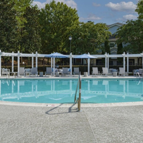 a swimming pool with trees and a building in the background