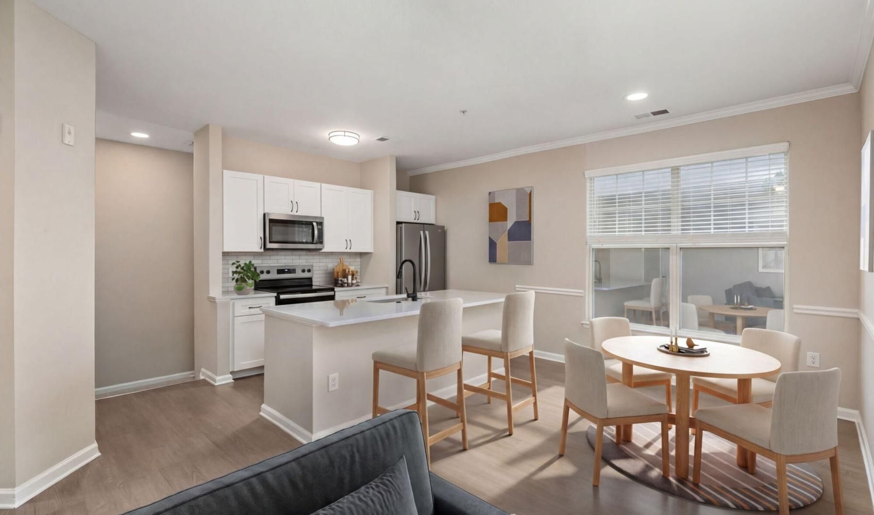 a living room with furniture and a kitchen with large windows